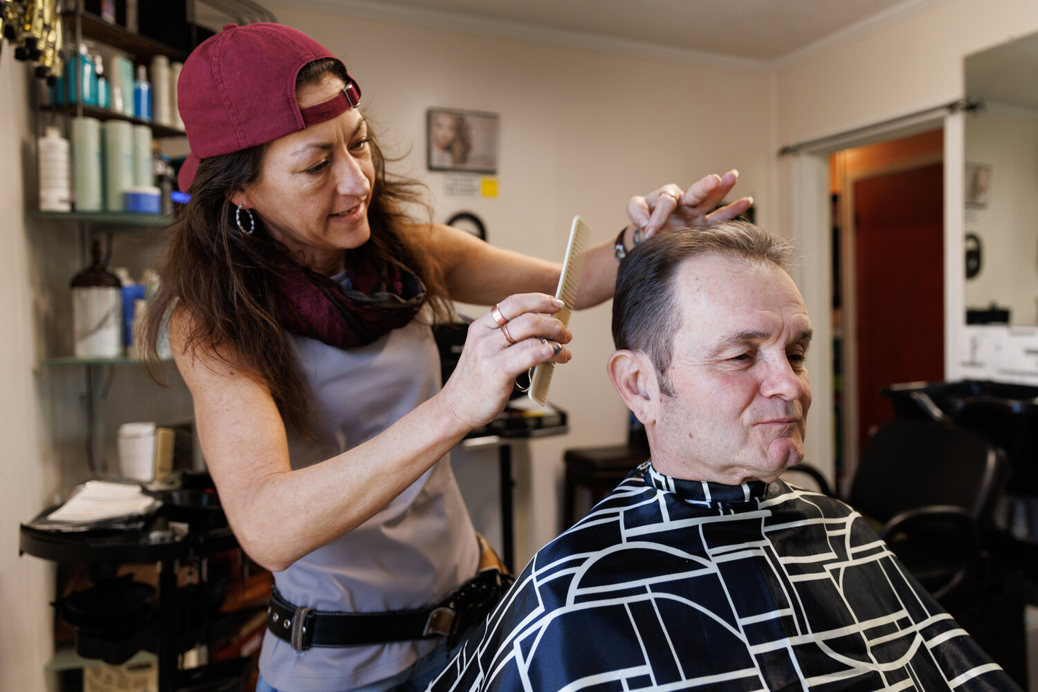 Stylist Sabrina Heeks trims Mike Costello's hair at Scissors on Marlborough salon. Mike enjoys the experience and considers it a necessary part of his self-care routine.