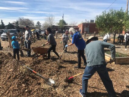 PNM volunteers shovel mulch for a community garden project on Albuquerque's westside