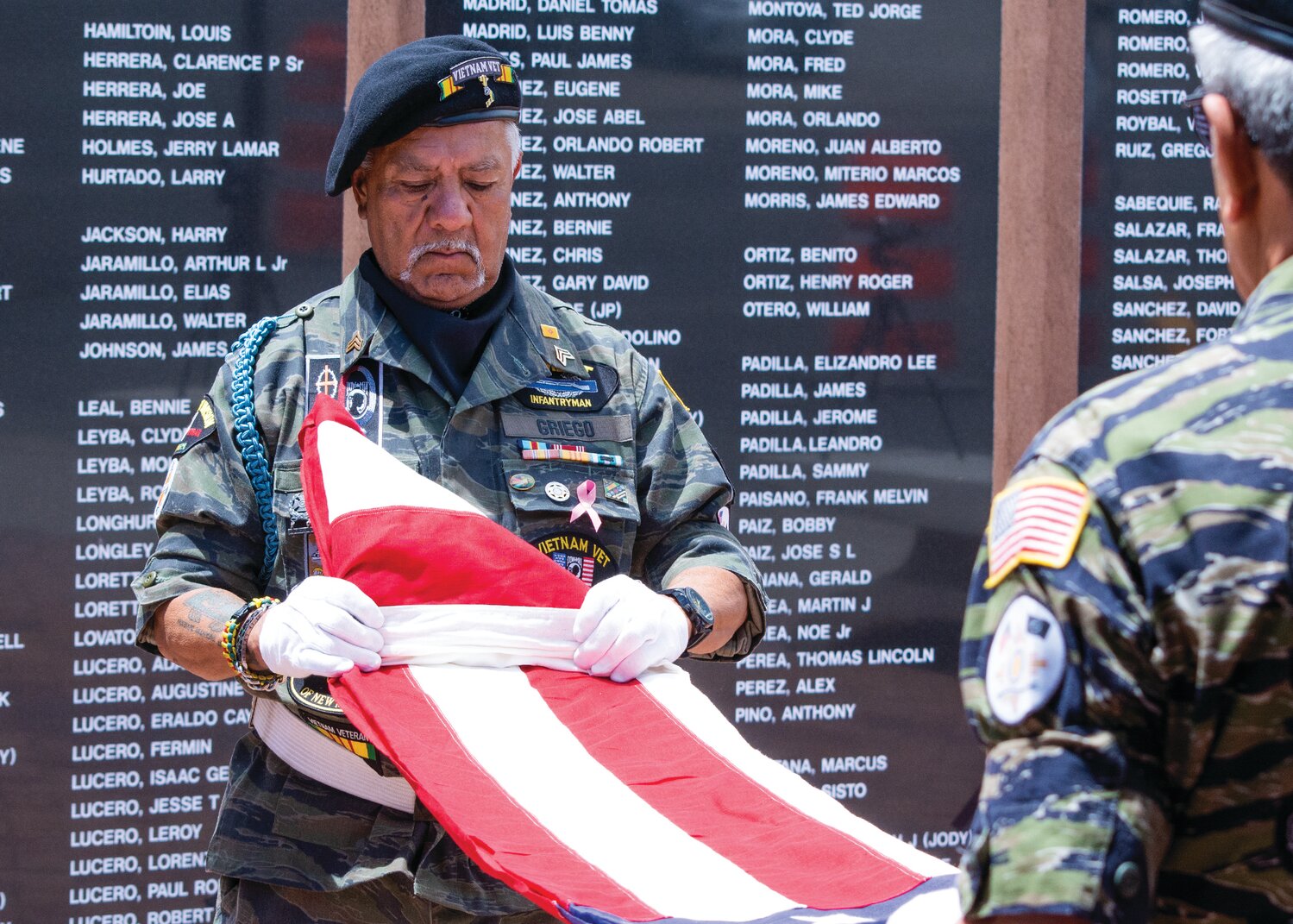 Two members of a Vietnam Veterans of America Northern New Mexico Chapter color guard fold the U.S. flag during 2017 Memorial Day Ceremonies at the Sandoval County Vietnam Veterans Memorial in Bernalillo.  The Veteran's Administration chose Bernalillo County as the site for a national cemetery, though it looked for a whole Sandoval County had the inside track. (Bill Diven/Sandoval Signpost)