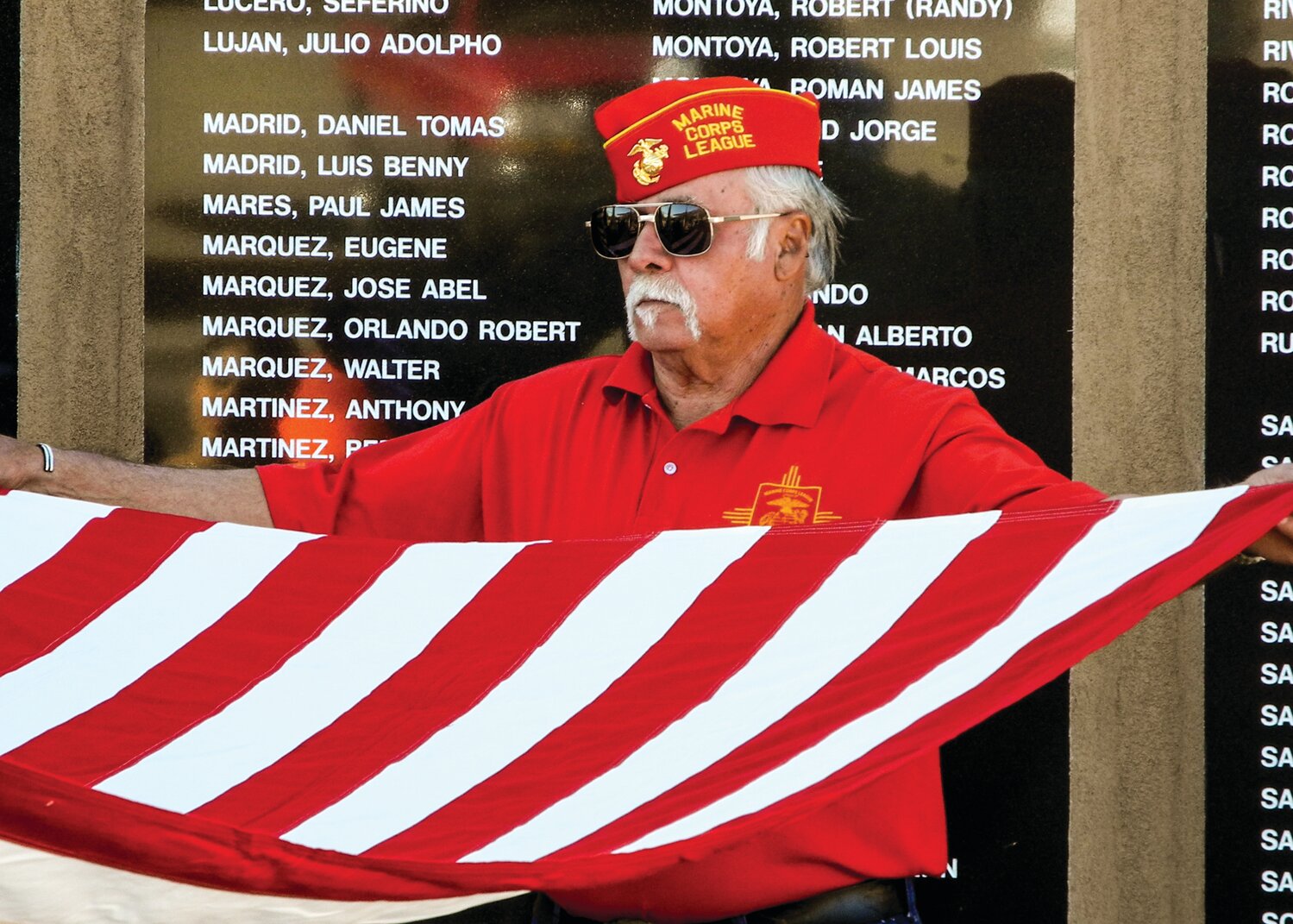 A Marine Corps veteran helps fold the U.S. flag during 2014 Memorial Day ceremonies at the Sandoval County Vietnam Veterans Memorial in Bernalillo. (Bill Diven/Sandoval Signpost)