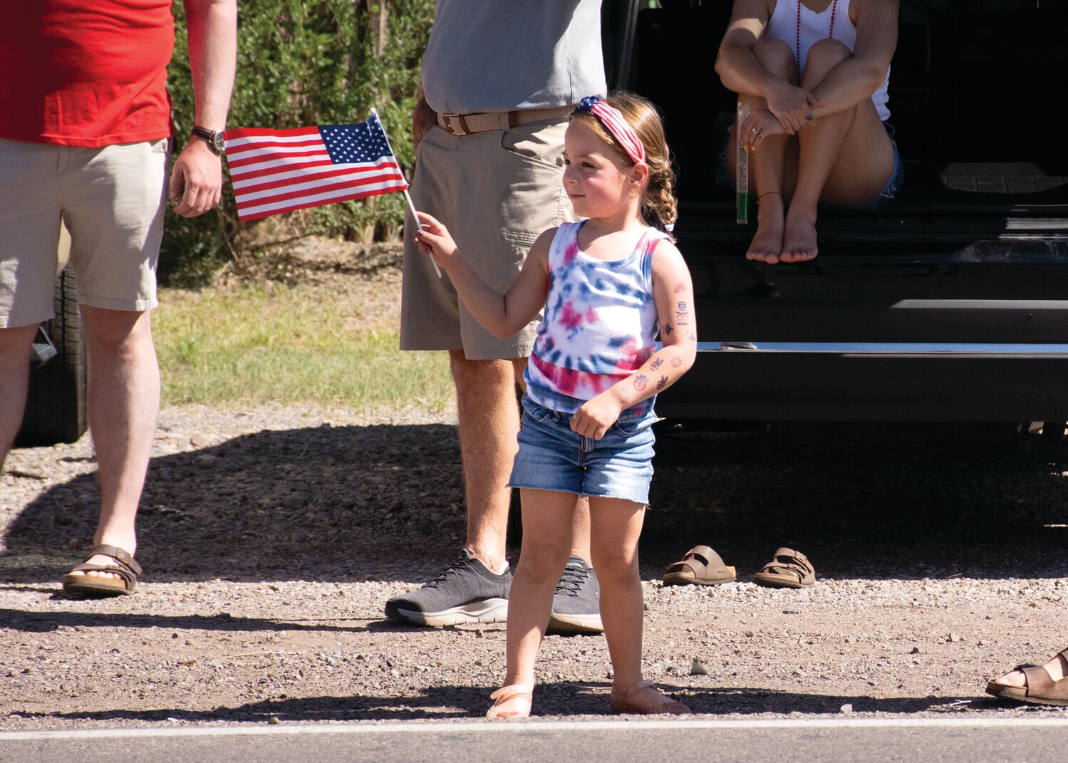 Aurelia Roberts of Placitas waves the flag while watching the parade pass and waiting for another handful of candy to be thrown in her direction.