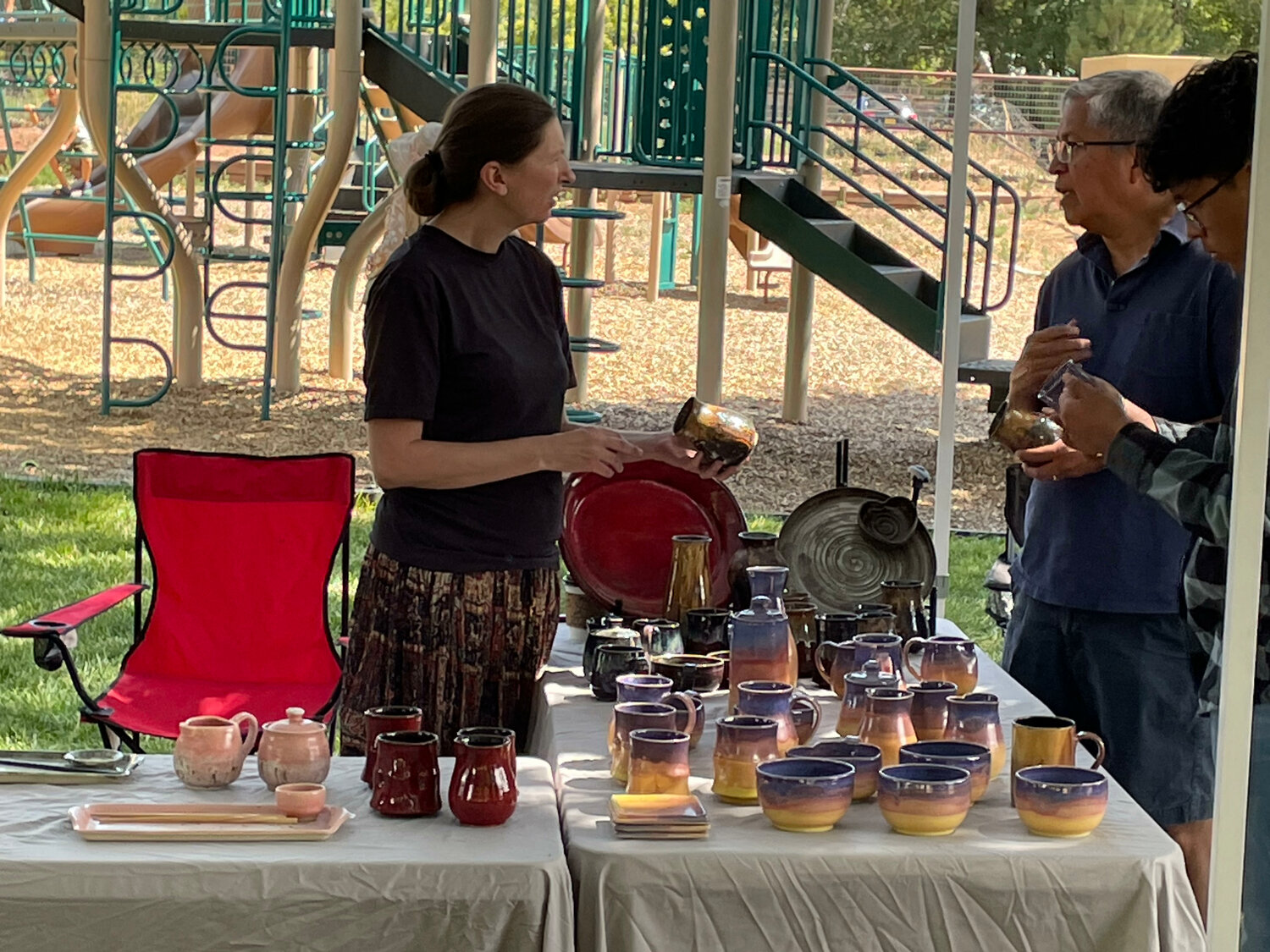 Jen Noel, president of the Corrales Society of Artists, speaks to customers during Arts in the Park on July 8. The popular event returned to La Entrada Park after a three-year absence. (T.S. Last/Corrales Comment)