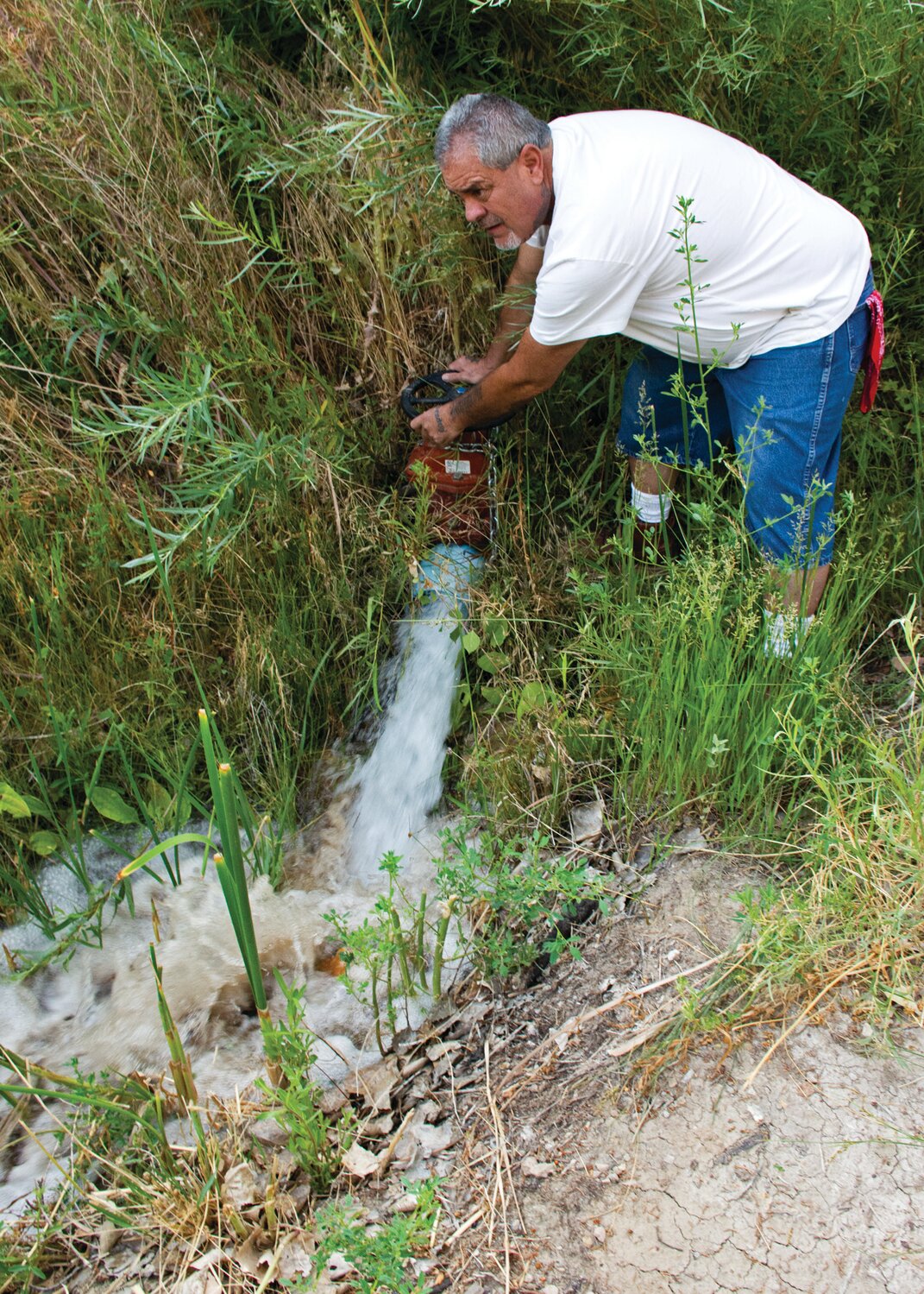 Mayordomo Harvey Vigil of Las Acequias de Placitas monitors the flow of irrigation water coming for Ciruela tank and springs on a separate ditch that meet here.