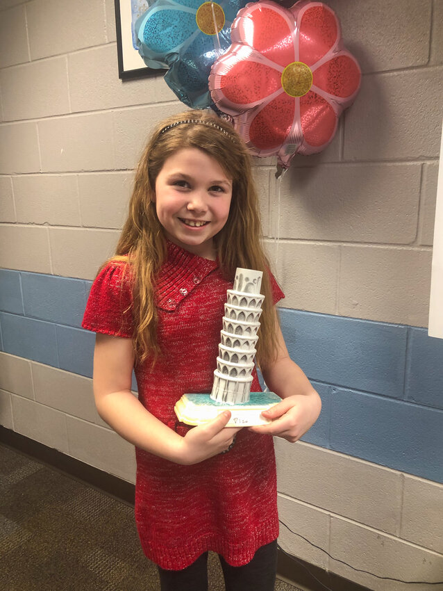 Sammi Alexander holds her Leaning Tower of Pisa creation, which she put together out of bottlecaps. The piece of art, along with other works of hers, is on display through the end of April at the Genoa Branch Library at 602 West St. in Genoa.