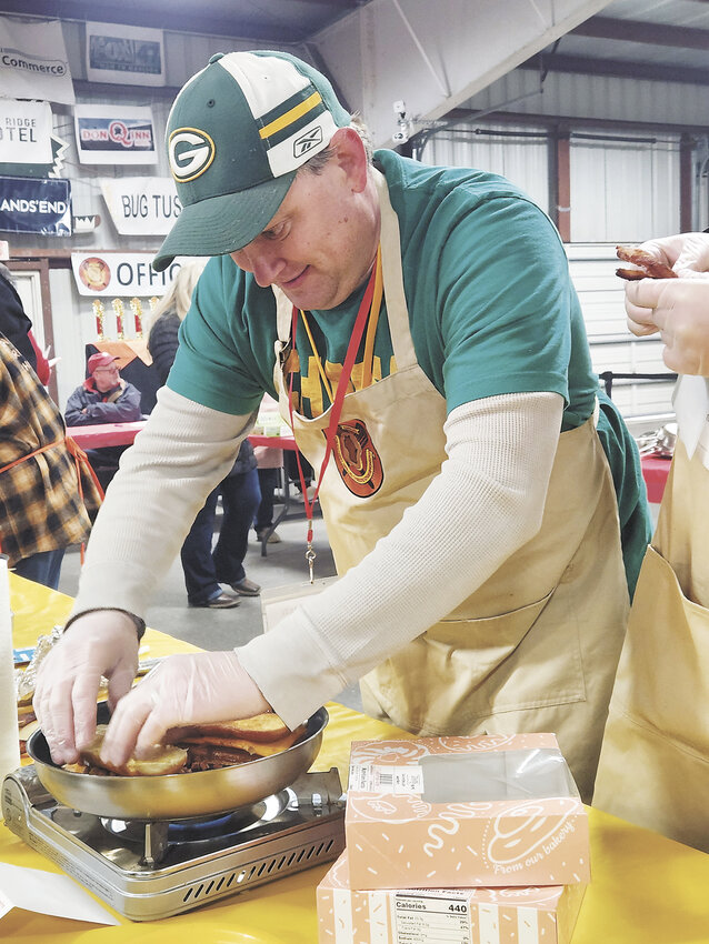 Zach Washa puts the finishing touches on his grilled cheese sandwich April 20 at the Wisconsin Grilled Cheese Championship in Dodgeville, Wisconsin. For his eighth year of competition, Washa created a recipe with Kwik Trip maple glazed donuts, bacon and cracked pepper cheddar cheese and won second place.