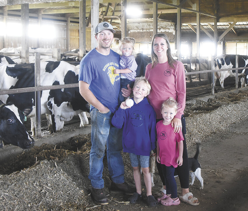 The Kahl family — Tucker (front, from left) and Palmer; (back, from left) Travis, Sayler and Sarah — stand in the freestall barn July 1 on their farm near Buckman, Minnesota. The Kahls have been filming farm videos since February 2023.