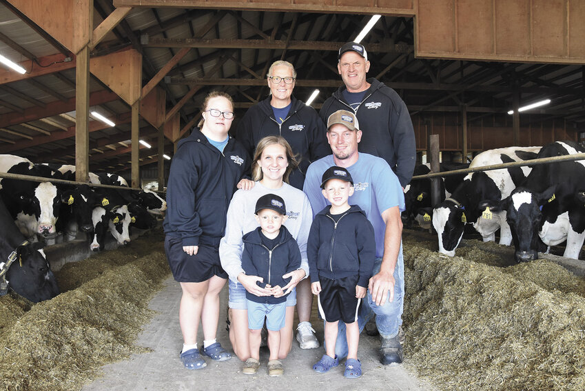 The Engelmeyers — Colton (front, from left) and Wyatt; (middle, from left) Amber and Derek; (back, from left) Emily, Kim and Joe — gather in their freestall barn Sept. 2 on their dairy near Melrose, Minnesota. Derek started helping full time on the farm in 2022.