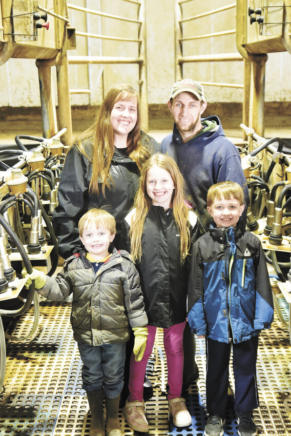The Rewitzer family — Harvey (front, from left), Jazlyn and Maverick; (back, from left) Skyla and Matt — gathers in their parlor March 11 at their farm near Bellingham, Minnesota. The Rewitzers purchased the farm in October 2024.