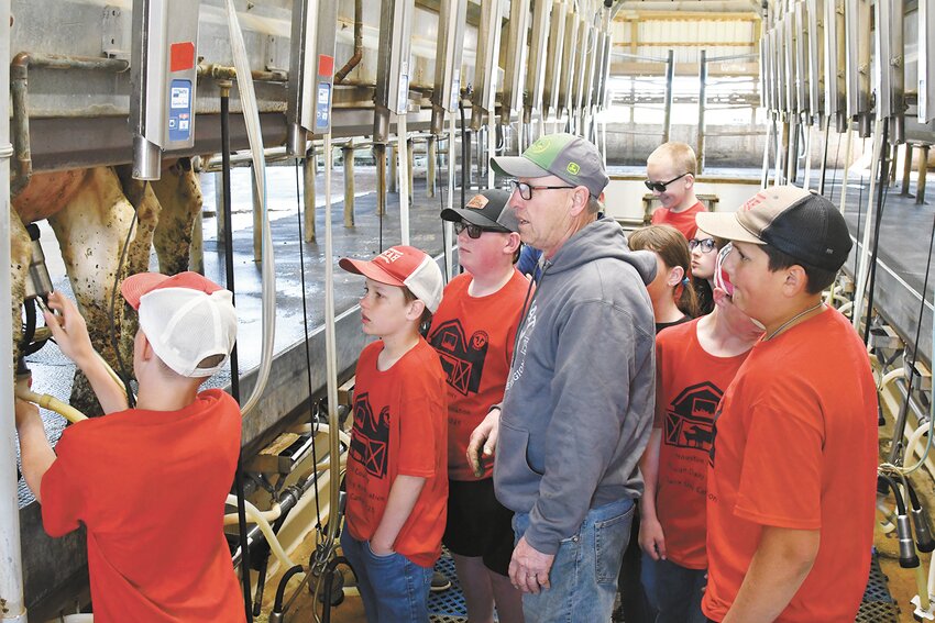 Joe Welscher (center) watches a student put on a milking unit at the 5th Grade Dairy Day Camp May 8 at Blue View Dairy near Caledonia, Minnesota. The dairy milks 300 cows.