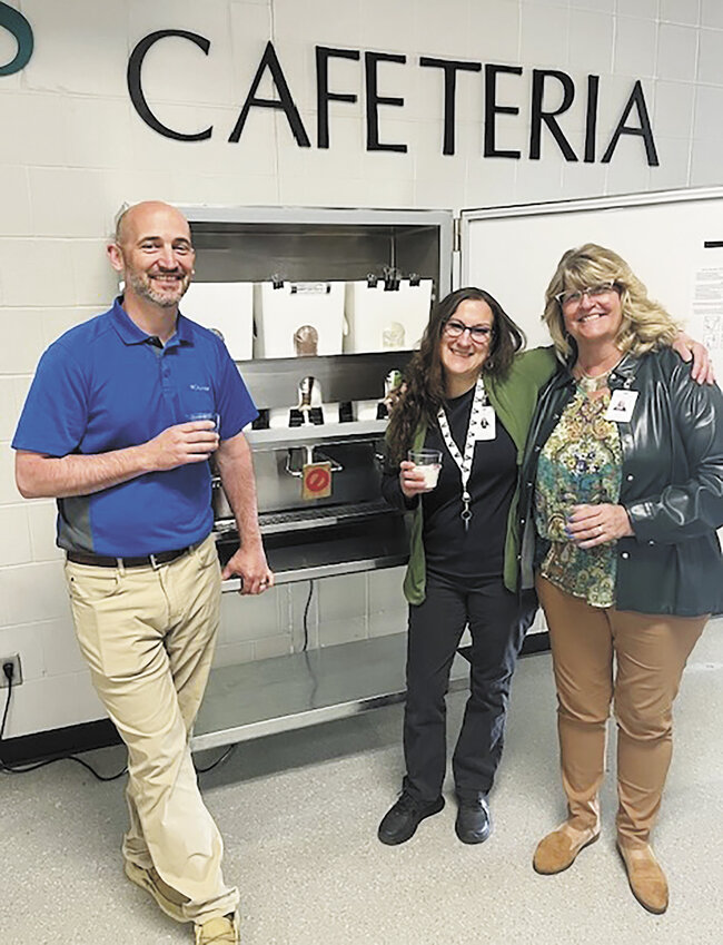 Superintendent Travis Okerlund (from left), food service coordinator Alyssa Wachsman and director of food service Sandy Gruber show the interior workings of one of two milk dispensers May 6 in the cafeteria at Albany Area Secondary School in Albany, Minnesota. School personnel worked together to make a smooth transition from cartons to dispensers.