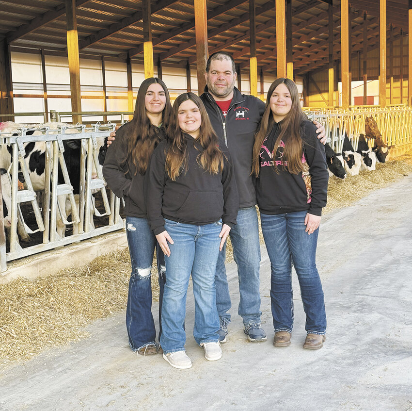 Jarrod Kollwelter and his daughters, Paige (from left), Jaclyn and Brianna, gather next to one of their heifer barns Feb. 27 on their farm near Whitewater, Wisconsin. The Kollwelters milk 240 cows with a herd average of 38,300 pounds of milk, with tests of 4.3% butterfat and 3.1% protein.