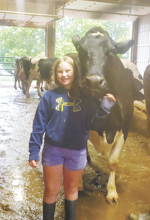 Zaryn Popp smiles next to a cow this spring at her family’s farm near Pierz, Minnesota. The Popp family milks 145 cows.