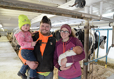 Evan and Taylor Schrauth with their children – (from left) Briella and McKenly – stand in the barn they began renting in October near Fond du Lac, Wisconsin. The Schrauths milk 80 cows but hope to be milking 95 shortly. PHOTO BY STACEY SMART