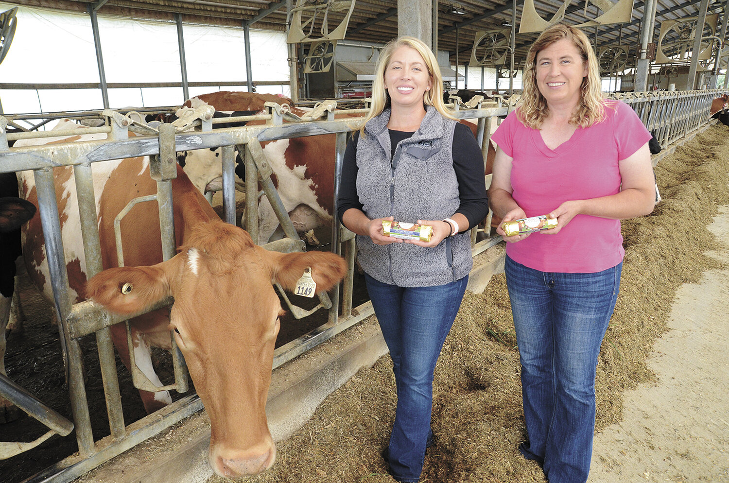 Jen (left) and Julie Orchard pose next to a favorite Guernsey Sept. 7 with butter made from their farm’s milk near Columbus, Wisconsin. Julie and her husband, Ed Bacon, milk 120 cows and farm 800 acres.