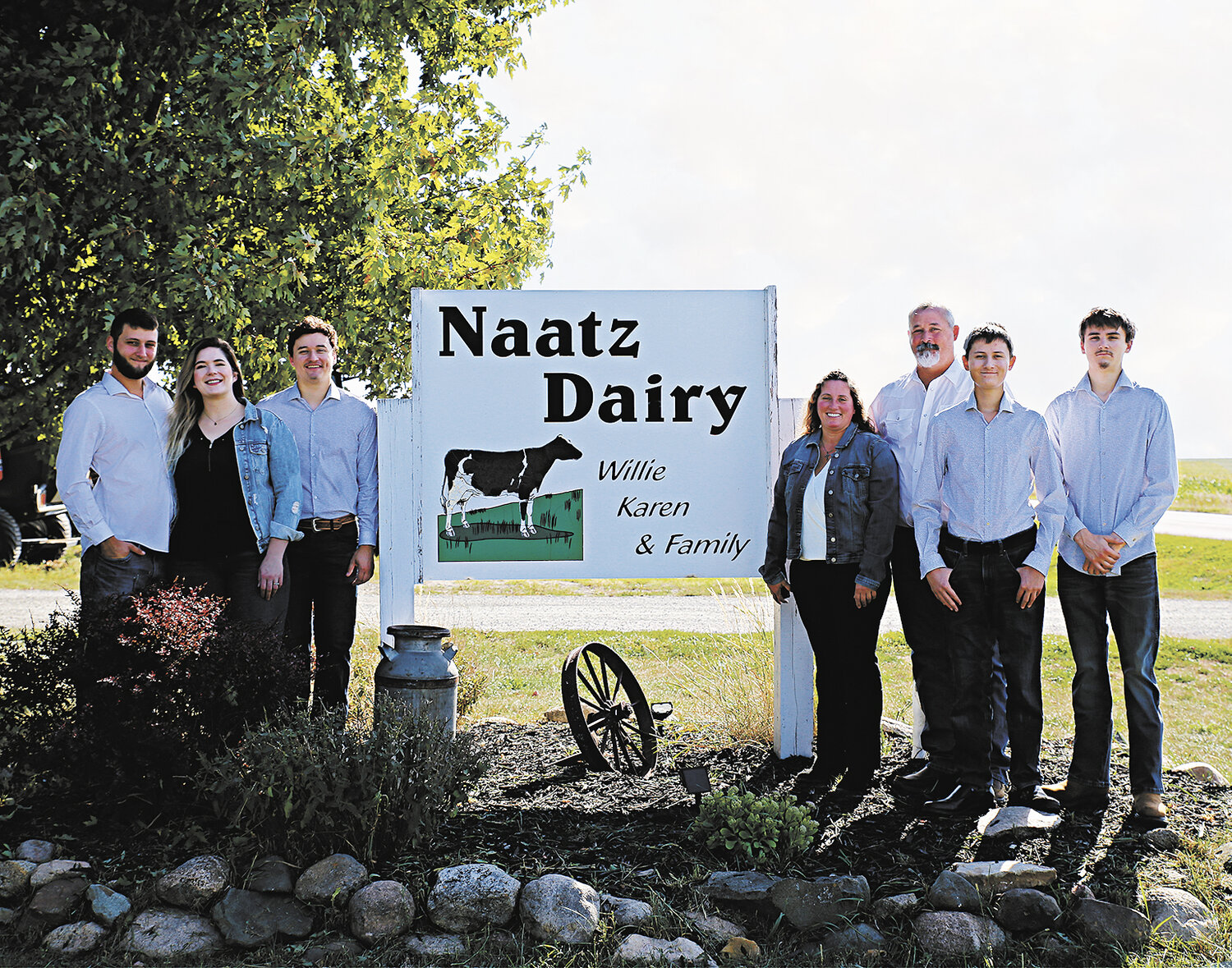 Tristin (from left), River, Trace, Karen, Willie, Wyatt and Brodee Naatz stand by their farm sign in September near Mantorville, Minnesota. The Naatzes milk 250 cows.