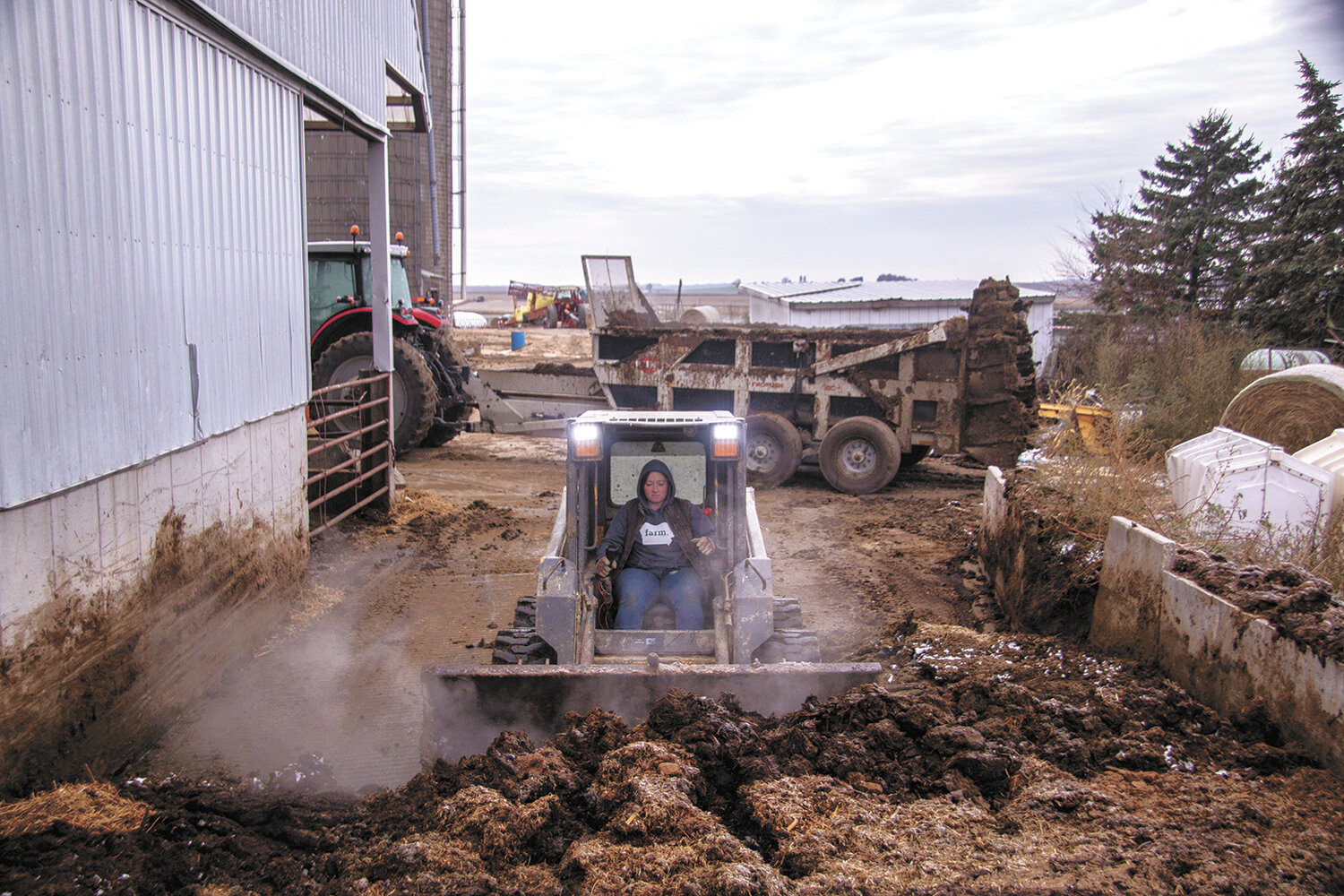 Mindy Burkle scoops up manure with a skid loader Nov. 1 at the Burkle family farm near Earlville, Iowa. Burkle returned home after college to farm full time with her dad.