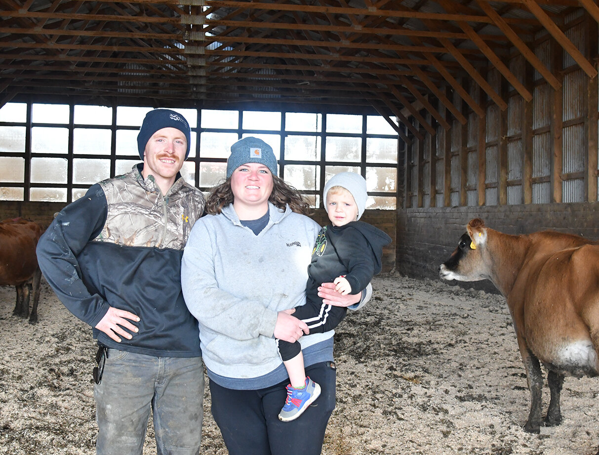 Bradley and Katie Fancsali, holding Buckley, smile Nov. 14 in a shed on their farm near Hayfield, Minnesota. The Fancsalis bought their farm in 2022.
