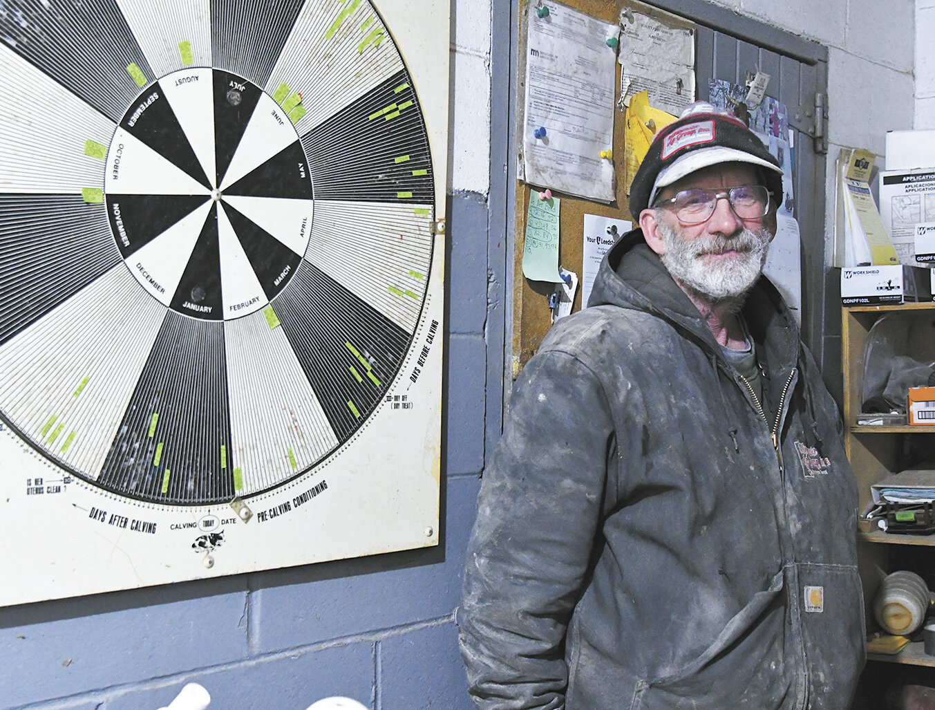 Patrick O’Brien smiles by his herd wheel Jan. 26 on his dairy farm near Kasson, Minnesota. O’Brien uses the herd wheel on his milkhouse wall to record calving and breeding information.