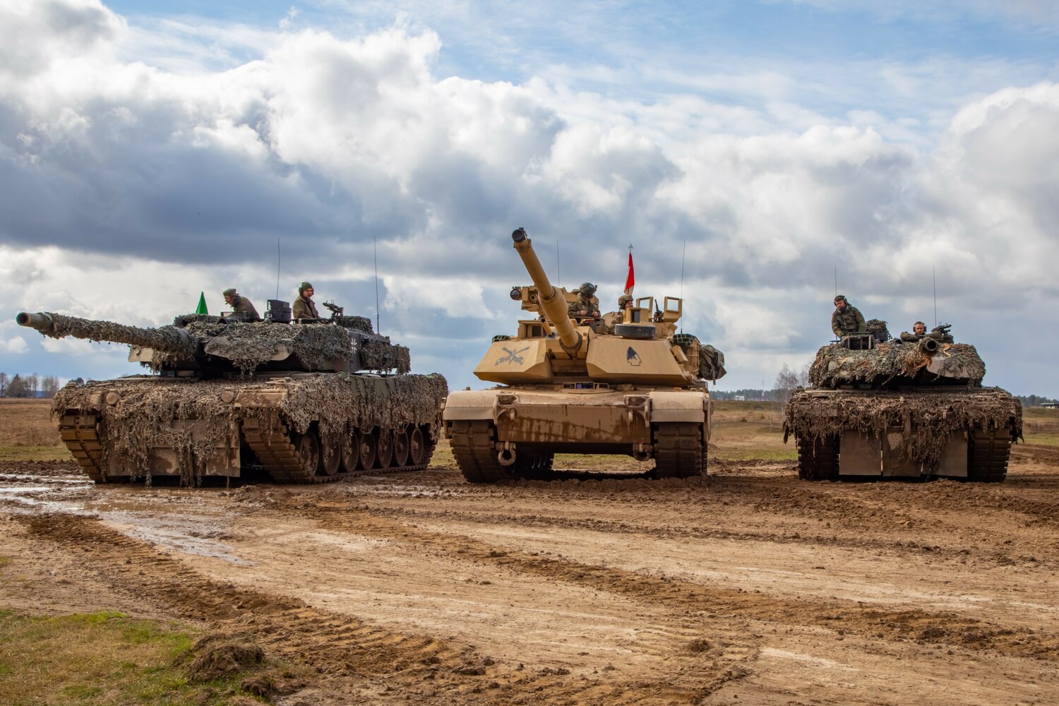 U.S. Soldiers position an M1A2 Abrams tank between German Leopard 2A6 tanks during a combined live fire exercise at Bemowo Piskie, Poland, April 4, 2023.