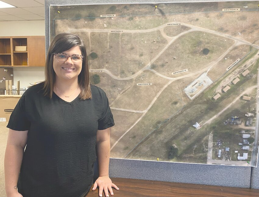 Cemetery Coordinator Kelsey Cole is pictured standing next to a detailed map of Restland Cemetery, which was founded in 1942.