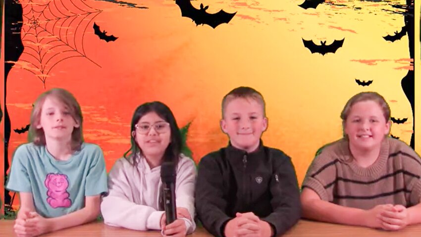 Anchors Derek Lundschen, Sophia Olvera Ortiz, Landon Smith, Kealie Lynch, sit in front of the green screen during their Halloween broadcast.