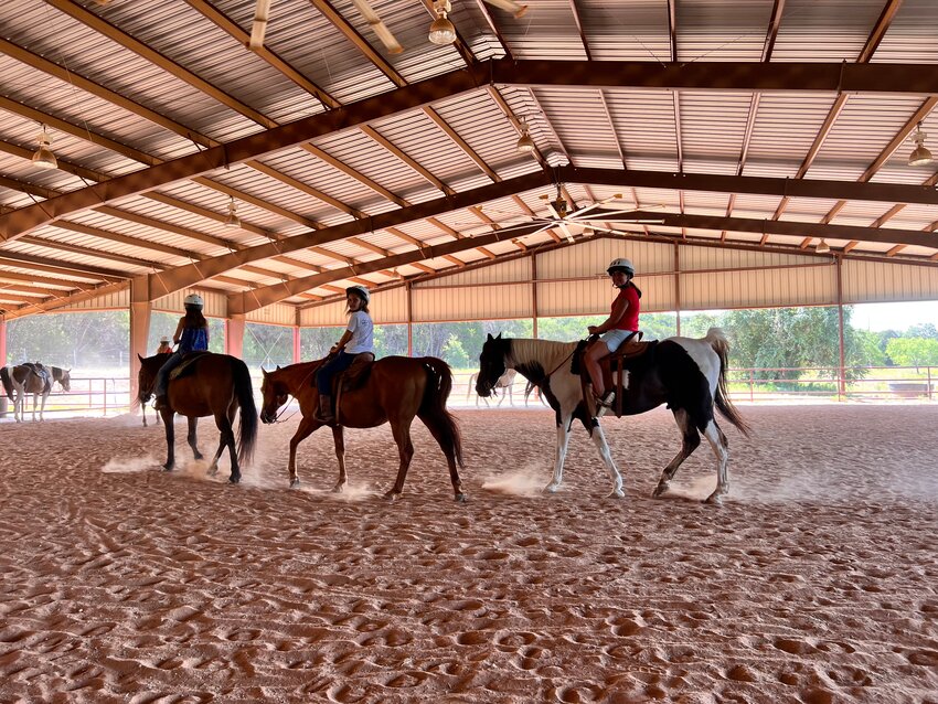 Campers on horseback riding in the arena at Camp El Tesoro.