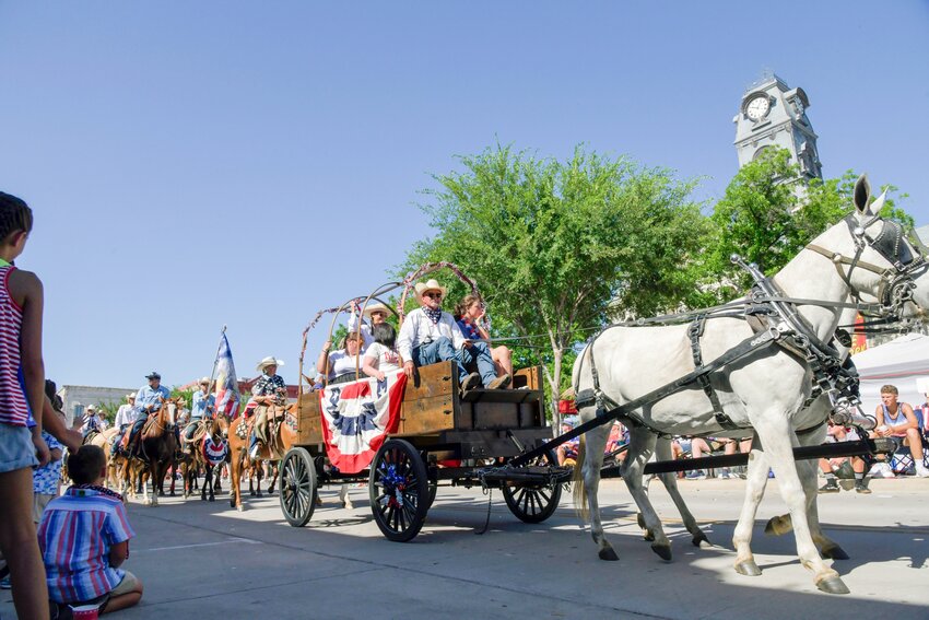 A chuckwagon in the 2024 July 4th parade passing the Hood County historic courthouse.