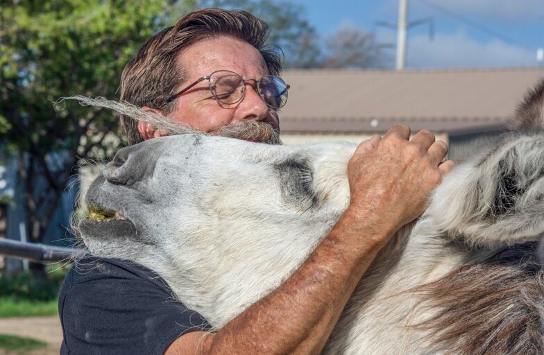 Tracy Miller gives a heartfelt hug to one of his rescue animals. He said he hopes after coming to the spaghetti western fundraiser that community members will start to see the kindness that these animals have and realize why board members and donors “all fall in love with these animals.” 