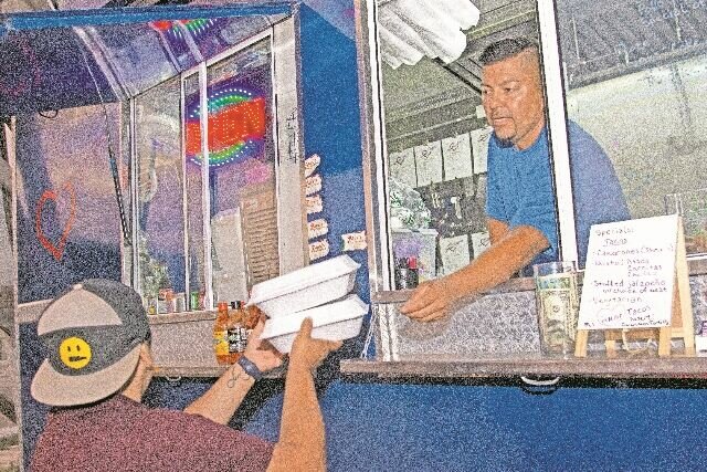 ORDER UP: Juan Martinez hands food to a customer through Mi Amor's order window.