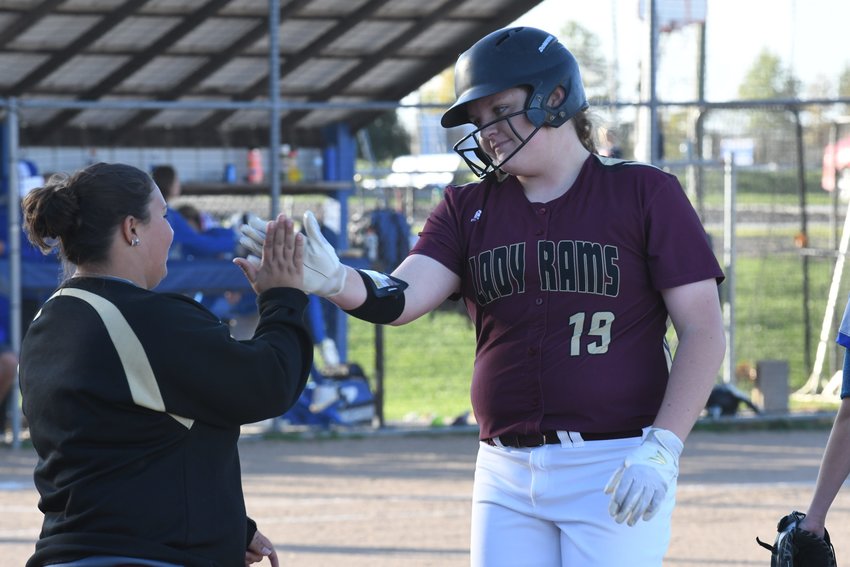 Schuyler County pitcher Kait Hatfield high-fives assistant coach Shelby Salter after drawing a walk Monday against Scotland County.