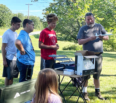 Adult leader Mark Bowen explains how to load an engine and igniter.