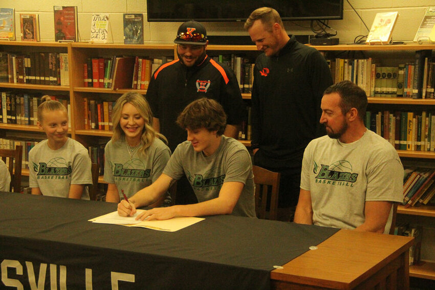 Kirksville senior Isaac Danielson signs his letter to John Wood Community College with family and coaches looking on during a ceremony at the Kirksville High School Library on May 9.&nbsp;