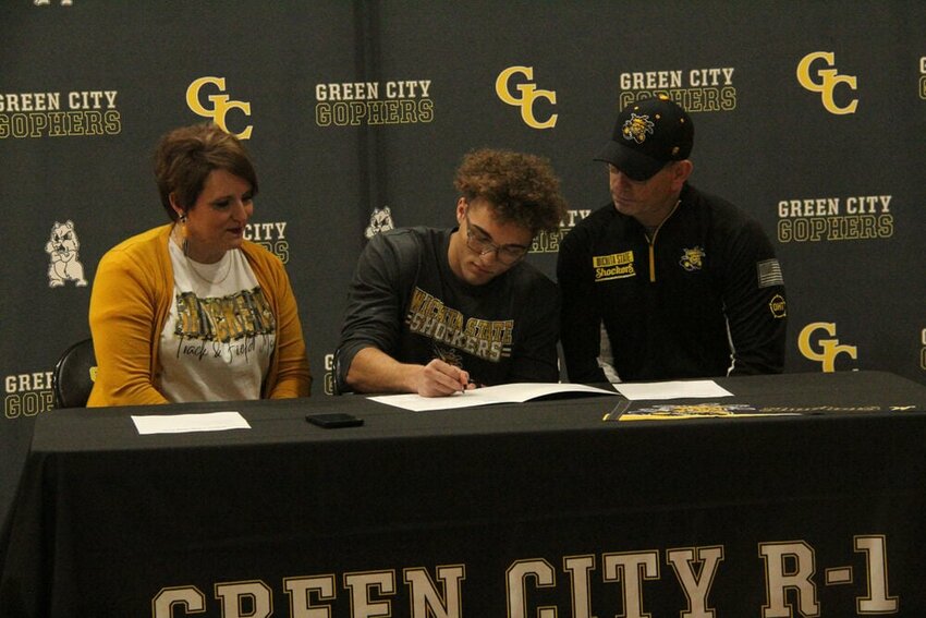Green City senior Asher Buggs-Tipton signs a letter to join the Wichita State track and field program during a ceremony in the Green City High School gym on Jan. 5. Seated next to Buggs-Tipton are his parents Mandy and Jamie Tipton.&nbsp;