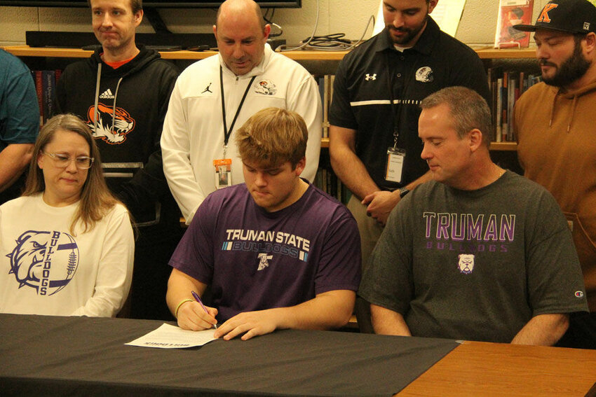Kirksville senior Michael Corbett signs his letter of commitment for Truman State football during a ceremony in the Kirksville High School library on Feb. 7.&nbsp;