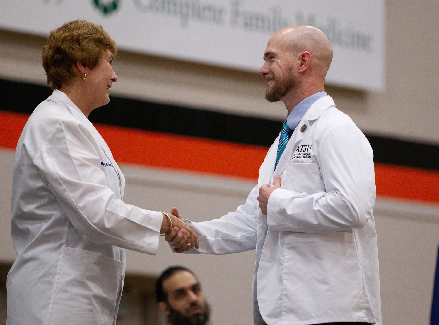 A.T. Still University-Kirksville College of Osteopathic Medicine Dean Dr. Margaret Wilson shakes hands with first-year student Travis Rushton during the White Coat Ceremony.