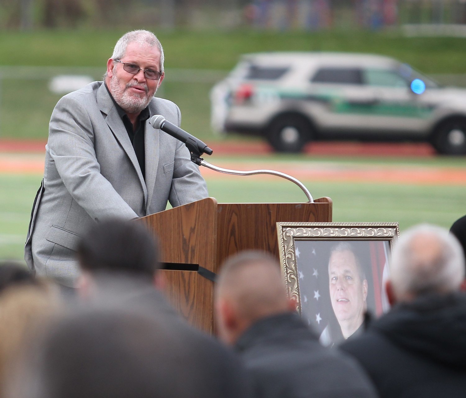 Doug McAntire, a lifelong friend of Steve Farnsworth, speaks as the officiant for Farnsworth's funeral Saturday at Spainhower Field.