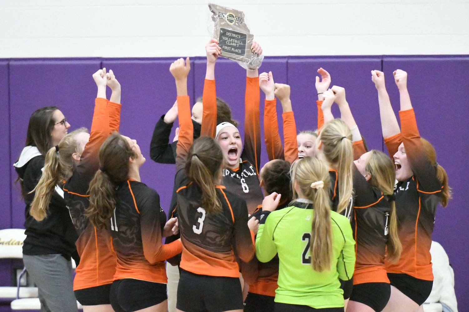 Kirksville senior middle hitter Emily Middleton hoists up the Class 3 District 7 trophy as her teammates cheer around her.
