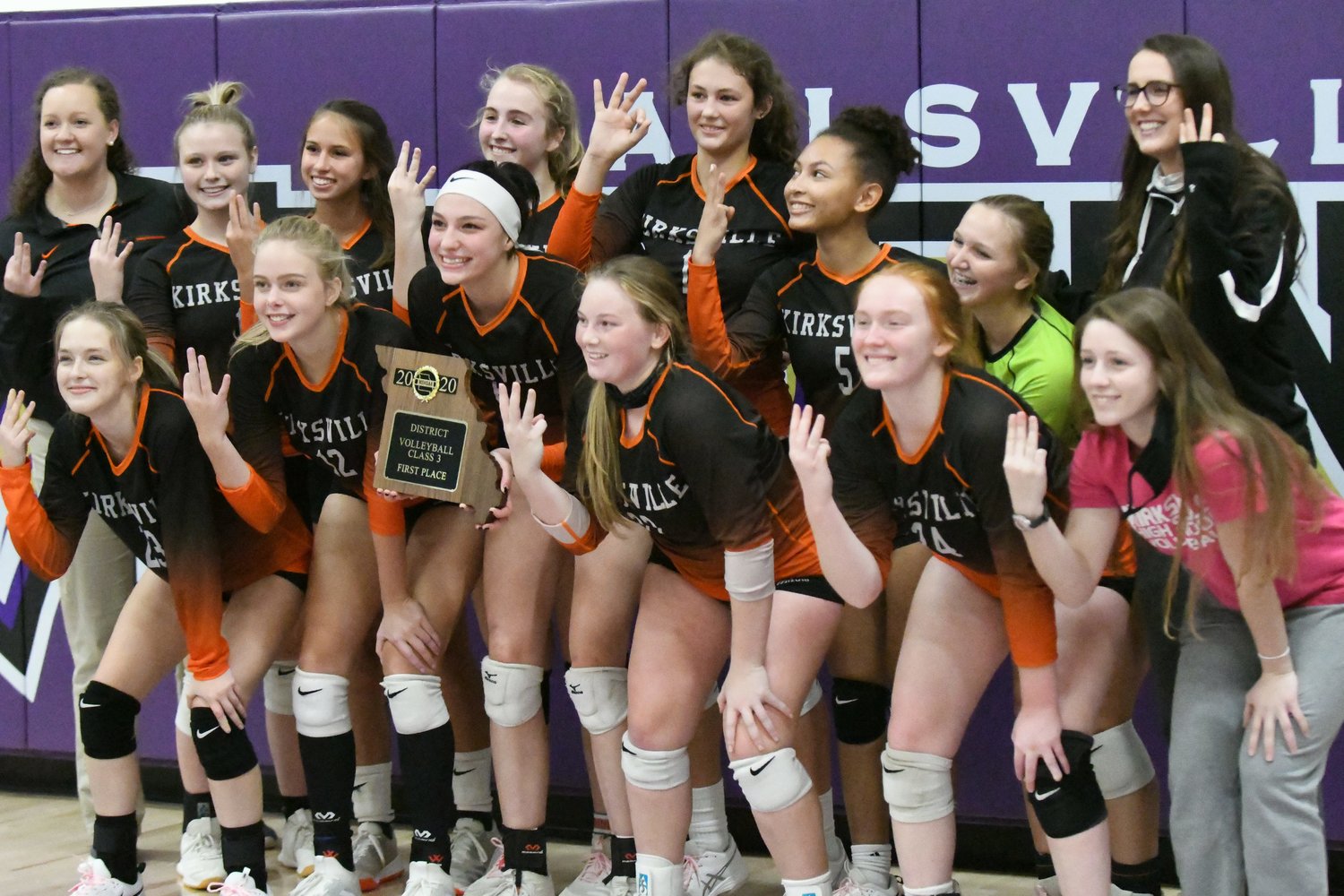 The Kirksville volleyball team holds up three fingers to commemorate its third straight district title.