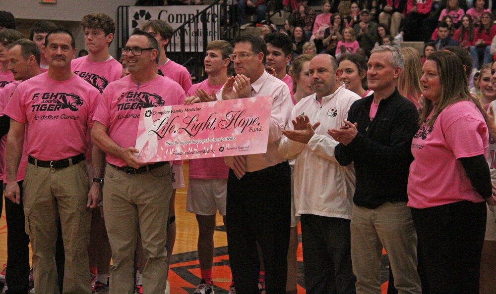 Dr. Justin Puckett (holding sign) poses with members of Kirksville High School athletics as a part of a ceremony for Pink Out Night that took place between the girls and boys varsity basketball games on Jan. 13. 
