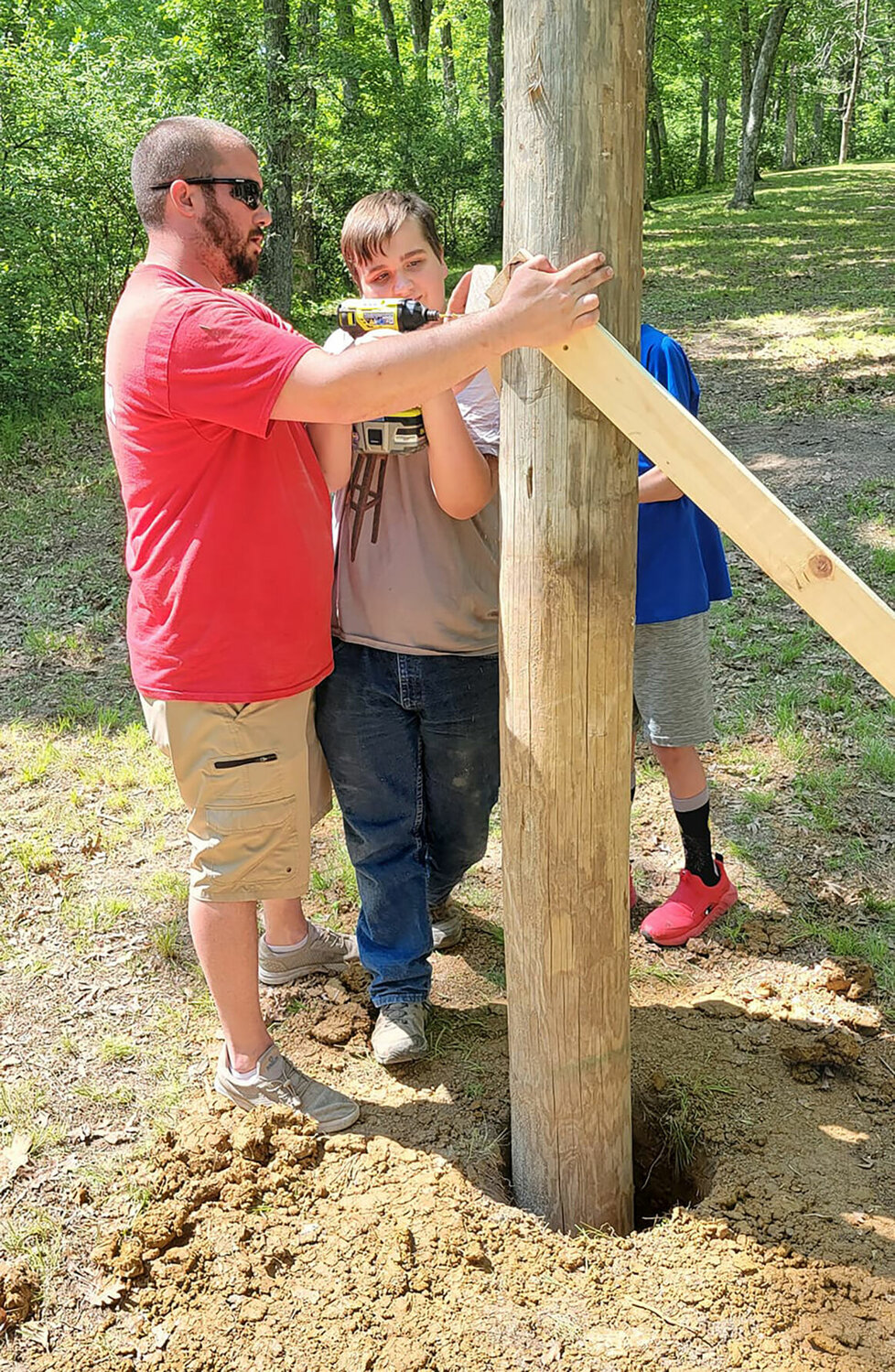 Tyler Lynak assists Cormac Nolan in setting the poles plumb while Nolan secures the temporary bracing.