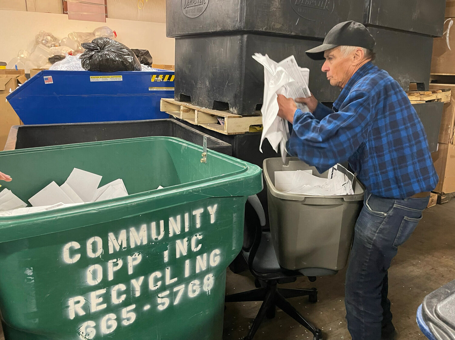 A worker at Community Opportunities loads sorted paper into a bin. 