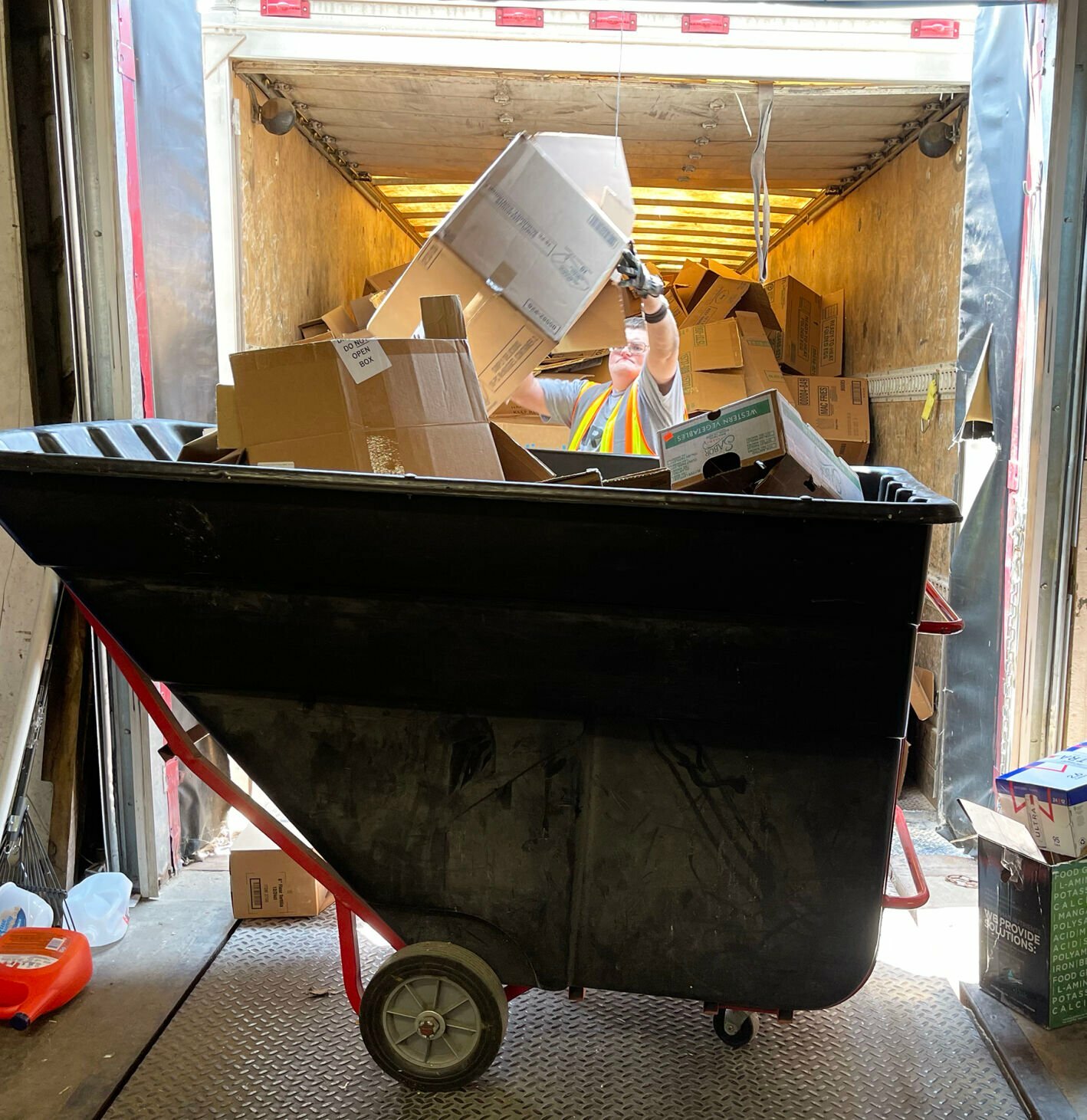 A worker at Community Opportunities unloads a truck full of cardboard. 