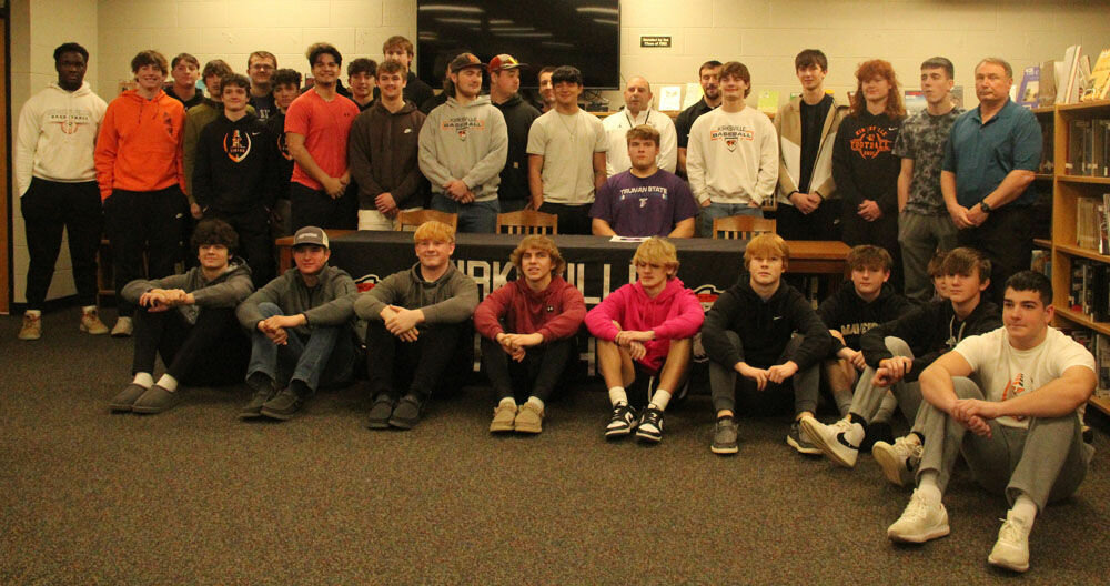 Kirksville senior Michael Corbett poses with football teammates and coaches in the Kirksville High School Library on Feb. 7. 