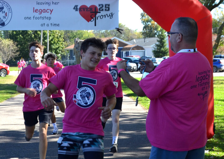 John Folk handed out medals as a pack of runners made a burst for the finish line at Wolf River Crossing Park. The 5K run is named after Taylor Kennedy Folk, a student-athlete that died before graduation in 2019. Every year, two scholarships are awarded in her name. .James Card Photo