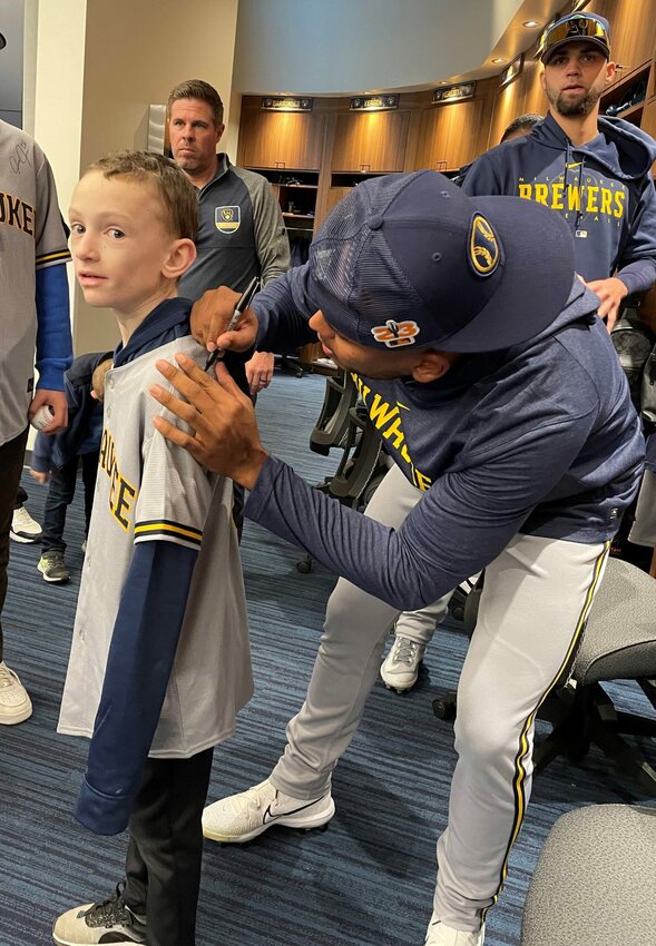 Milwaukee Brewers pitcher Freddy Peralta autographs Owen Strege of Algoma's new team jersey in the locker room at the Brewers' spring training camp in Phoenix. Strege was one of three boys from Wisconsin with pediatric health issues chosen by Aurora Health Care to be guests of the team for the first weekend of spring training and throw out the first pitch of the opening game Feb. 25.