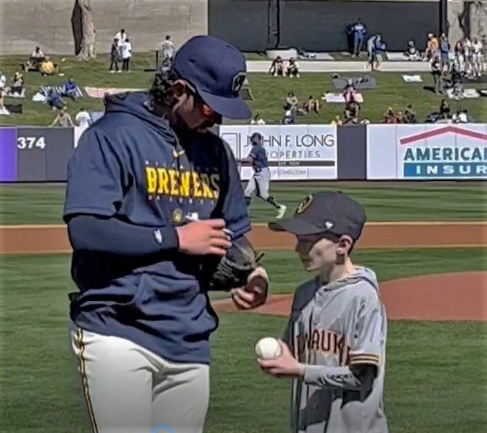 Milwaukee Brewers catcher Payton Henry autographs a baseball for Owen Strege of Algoma after Strege threw out the first pitch of the Brewers' first spring training game of 2023, Feb. 25 in at the Brewers' camp in Phoenix against the Los Angeles Dodgers. Strege was one of three boys from Wisconsin with pediatric health issues chosen by Aurora Health Care to be guests of the team that weekend.