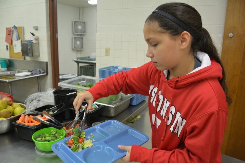 Madison Simons, a seventh-grader at Algoma Middle School, helps herself to fruits and vegetables from the school cafeteria. A new partnership announced this week will provide more locally sourced foods for the cafeteria.