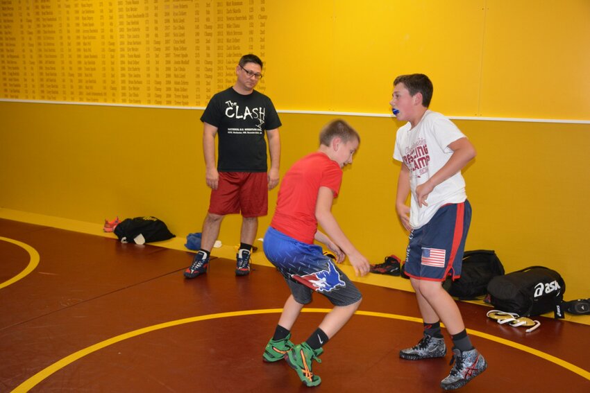 New Spartans head wrestling coach Chas Treml, left, brings middle school students into the wrestling program early.  Eighth-graders Lucas Joniaux and Gabe Zellner practice with the high school team.
