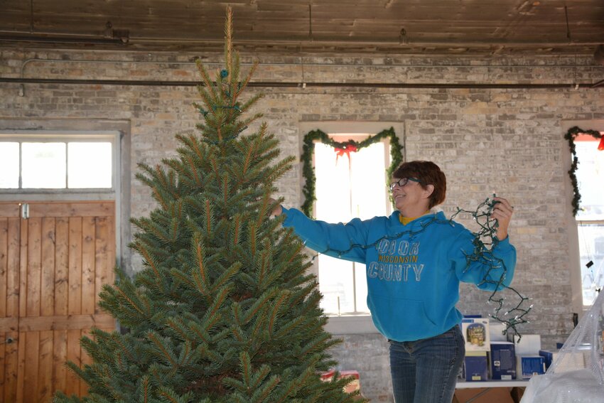 Eileen Heuer strings lights on a Christmas tree in preparation for Winter in the Village.