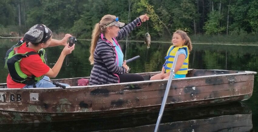 While her mom, Liz, captured the action on camera, 4-year-old Ainsley Melotte got some help from Tammy Naze after catching a bluegill on West Alaska Lake.